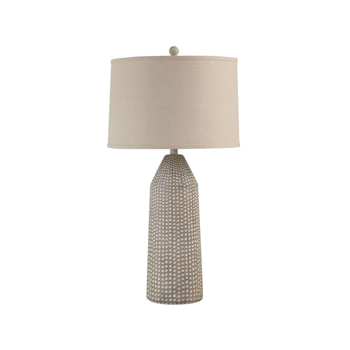 Table lamp with textured base and beige shade on a white background