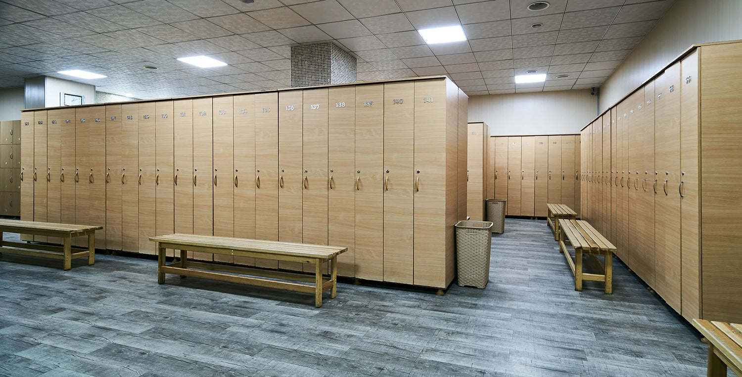 Wooden lockers and benches in a locker room with tiled floor and ceiling.