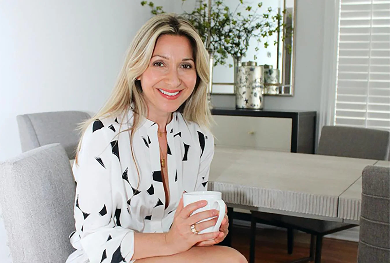 Laurie holding a mug in a living room setting