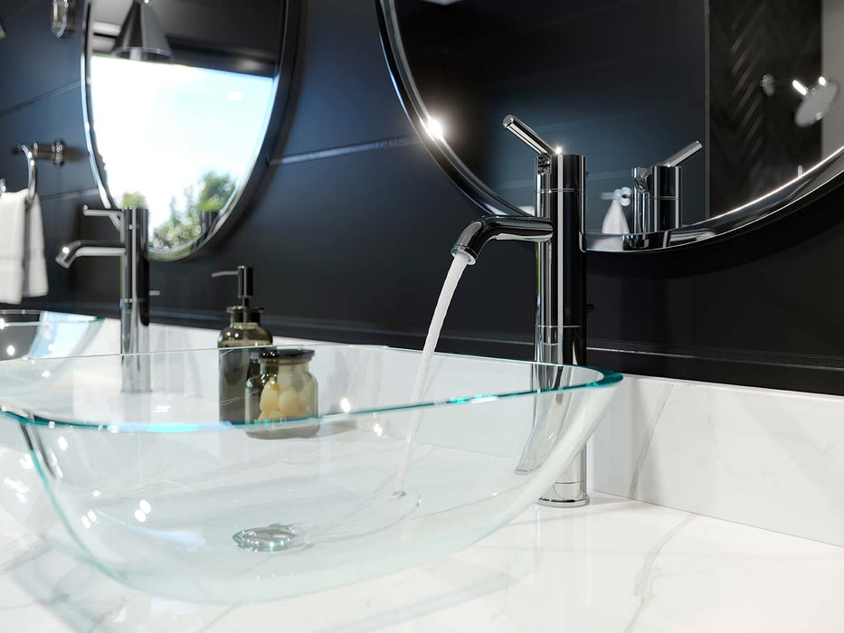 Pfister Contempra single-control vessel bathroom faucet in polished chrome, installed on a white modern marble countertop, with water flowing into a glass basin and round chrome-edged mirrors in a modern bathroom.