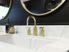 Pfister Contempra 2-handle 8-inch widespread bathroom faucet in brushed gold, installed on a white countertop in a contemporary bathroom, with water flowing smoothly from the spout.
