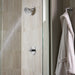 Pfister Contempra 1-handle shower set in polished chrome, with water flowing from the round showerhead in a modern neutral toned shower.