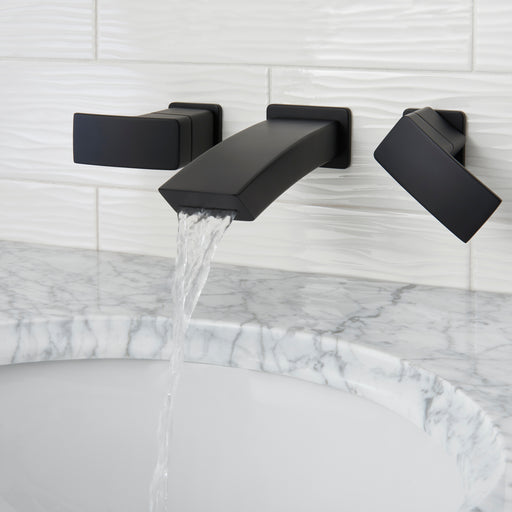 Pfister Kenzo 2-handle wall-mount bathroom faucet in matte black, installed above a white undermounted sink on a white marble countertop in a contemporary bathroom.