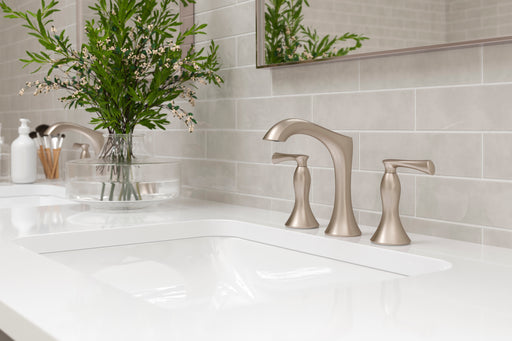 Pfister Rhen 2-handle 8-inch widespread bathroom faucet in brushed nickel, installed on a white countertop in a contemporary bathroom.
