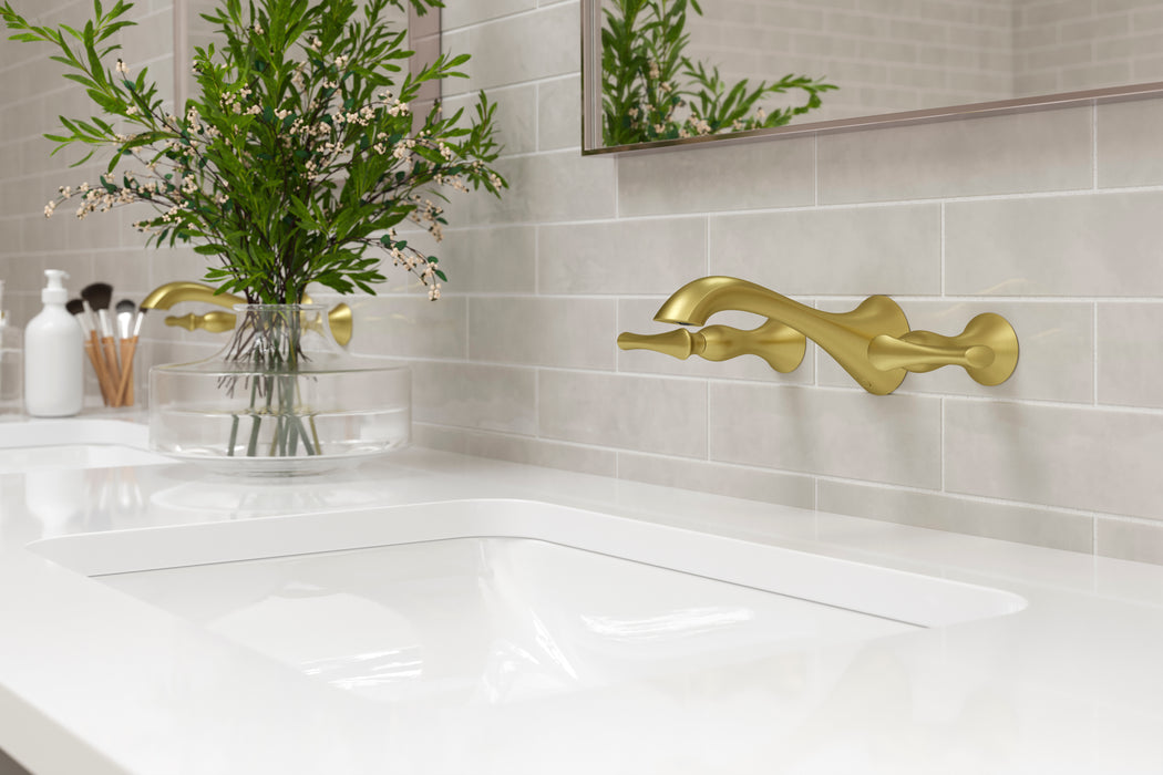 Pfister Rhen 2-handle wall-mount bathroom faucet in brushed gold, installed above a white undermounted sink on a sleek countertop in a contemporary bathroom.