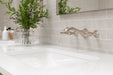 Pfister Rhen 2-handle wall-mount bathroom faucet in brushed nickel, installed above a white undermounted sink on a simple countertop in a transitional bathroom.