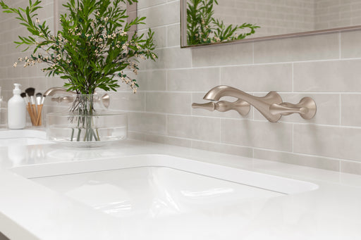Pfister Rhen 2-handle wall-mount bathroom faucet in brushed nickel, installed above a white undermounted sink on a simple countertop in a transitional bathroom.
