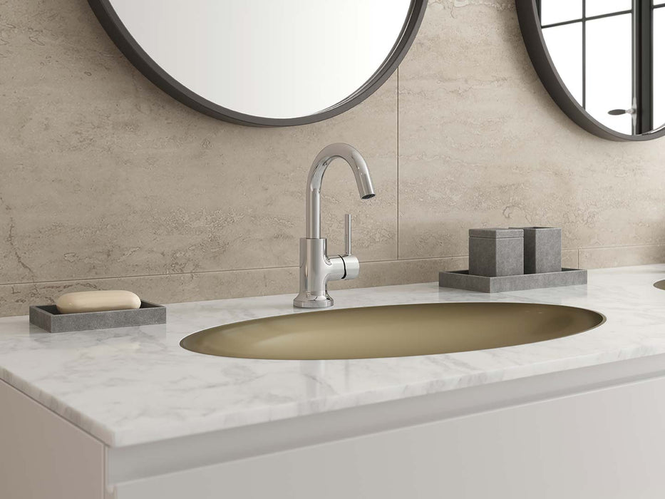 Pfister Tenet single-control bathroom faucet in polished chrome, installed on a white marble countertop with a matching gold sink, round mirrors, and minimalist decor.