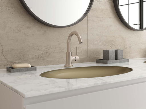 Pfister Tenet single-control bathroom faucet in brushed nickel, installed on a white marble countertop with a matching gold sink, round mirrors, and minimalist decor.