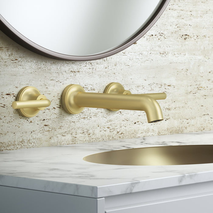 Pfister Tenet 2-handle wall-mount bathroom faucet in brushed gold, installed above a white undermounted sink on a simple, modern countertop.