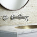Pfister Tenet 2-handle wall-mount bathroom faucet in polished chrome, installed above a white undermounted sink on a clean, modern countertop in a minimalist bathroom.