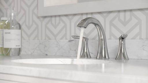 Pfister Weller 2-handle 8-inch widespread bathroom faucet in polished chrome, installed on a white marble countertop in a modern bathroom, with water flowing smoothly from the spout.
