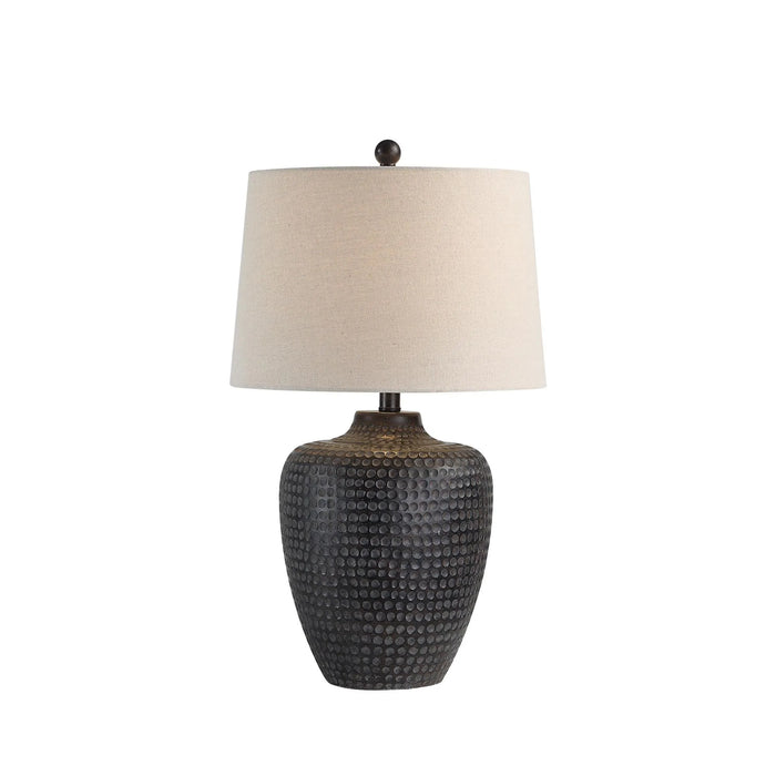 Table lamp with textured black base and beige lampshade on a white background