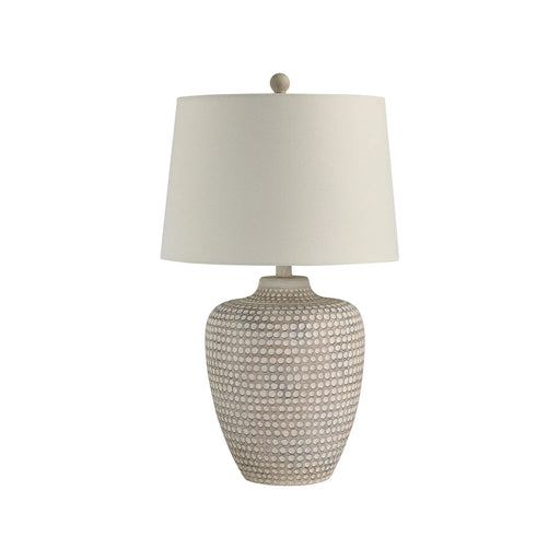 Table lamp with textured ceramic base and white shade on a white background