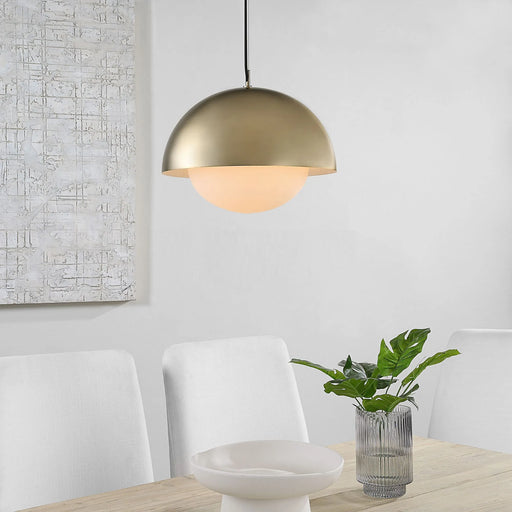 Gold pendant light fixture hanging above a dining table with chairs and a plant.