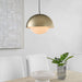 Gold pendant light fixture hanging above a dining table with chairs and a plant.