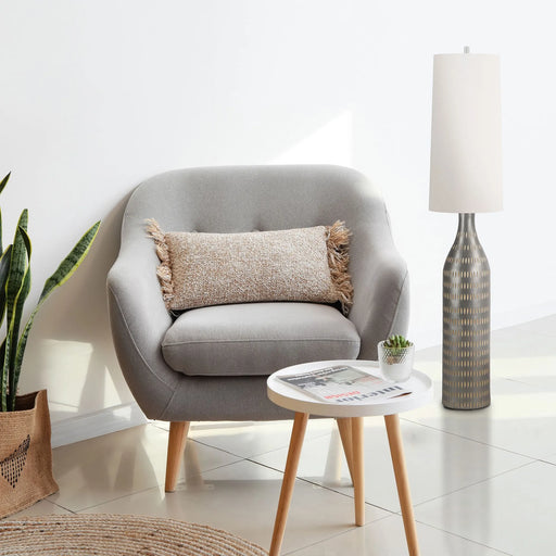 Gray armchair with a pillow, small round table, and a brown floor lamp in a modern living room.