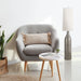 Gray armchair with a pillow, small round table, and a brown floor lamp in a modern living room.