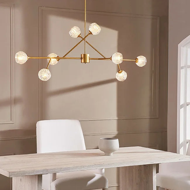 Modern chandelier hanging above a dining table with a neutral wall background