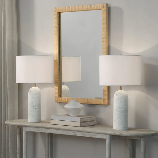 Two white table lamps on a wooden console table with a mirror above, against a gray wall.