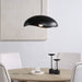 Black pendant dome light hanging above a dining table with white chairs.