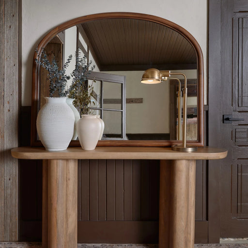 Wooden console table with a mirror, lamp, and vases in a room setting.