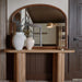 Wooden console table with a mirror, lamp, and vases in a room setting.