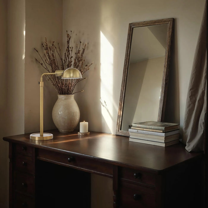 Wooden desk with lamp, vase, and mirror in a softly lit room