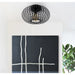 Black ceiling light fixture above a black abstract painting with white lines on a white wall.