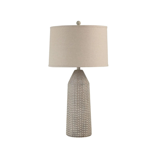 Table lamp with textured base and beige shade on a white background