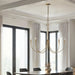 Gold chandelier hanging above a dining table with large windows and curtains in the background.