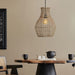 Woven pendant light hanging above a wooden table with black chairs and decor items.