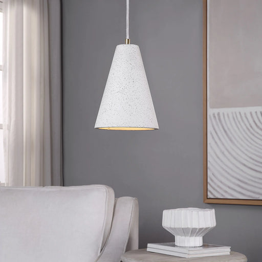 White textured pendant light hanging in a room with a gray wall, white sofa, and framed artwork.