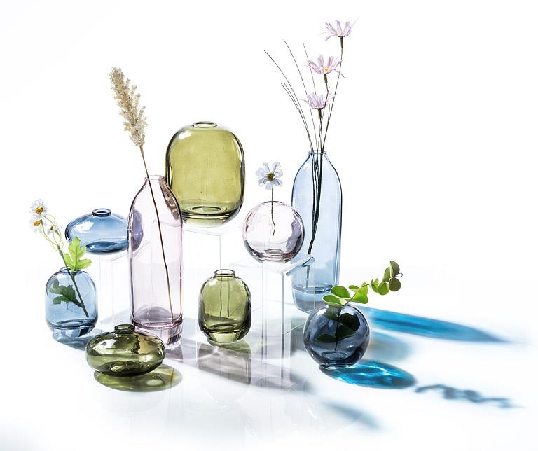 Abbott coloured glass vases arranged with flowers and decorative accents on a tabletop
