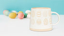 Patterned egg stoneware mug displayed with pastel Easter eggs in a spring setting