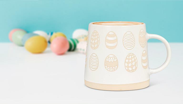 Patterned egg stoneware mug displayed with pastel Easter eggs in a spring setting