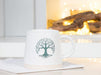 Ivory and green Tree of Life mug styled with coffee in a bright kitchen