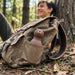 Asobu Besties Brown Bear insulated water bottle attached to a backpack outdoors