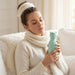 Woman relaxing indoors while holding the Asobu Kitty Bestie insulated stainless steel water bottle