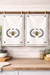 Set of 2 bee crest cotton kitchen towels hanging together in kitchen decor setting