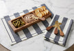 Blue and ivory striped cotton napkins styled beneath a wooden serving board