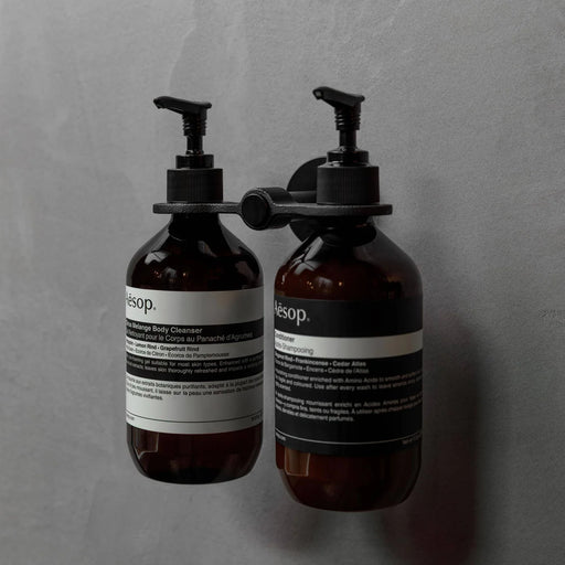 Buster + Punch Cast double dispenser soap holder in welders black finish holding amber soap dispenser bottles
