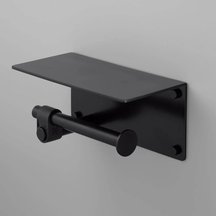 Angled view of Buster + Punch Cast toilet roll holder with shelf in welders black finish