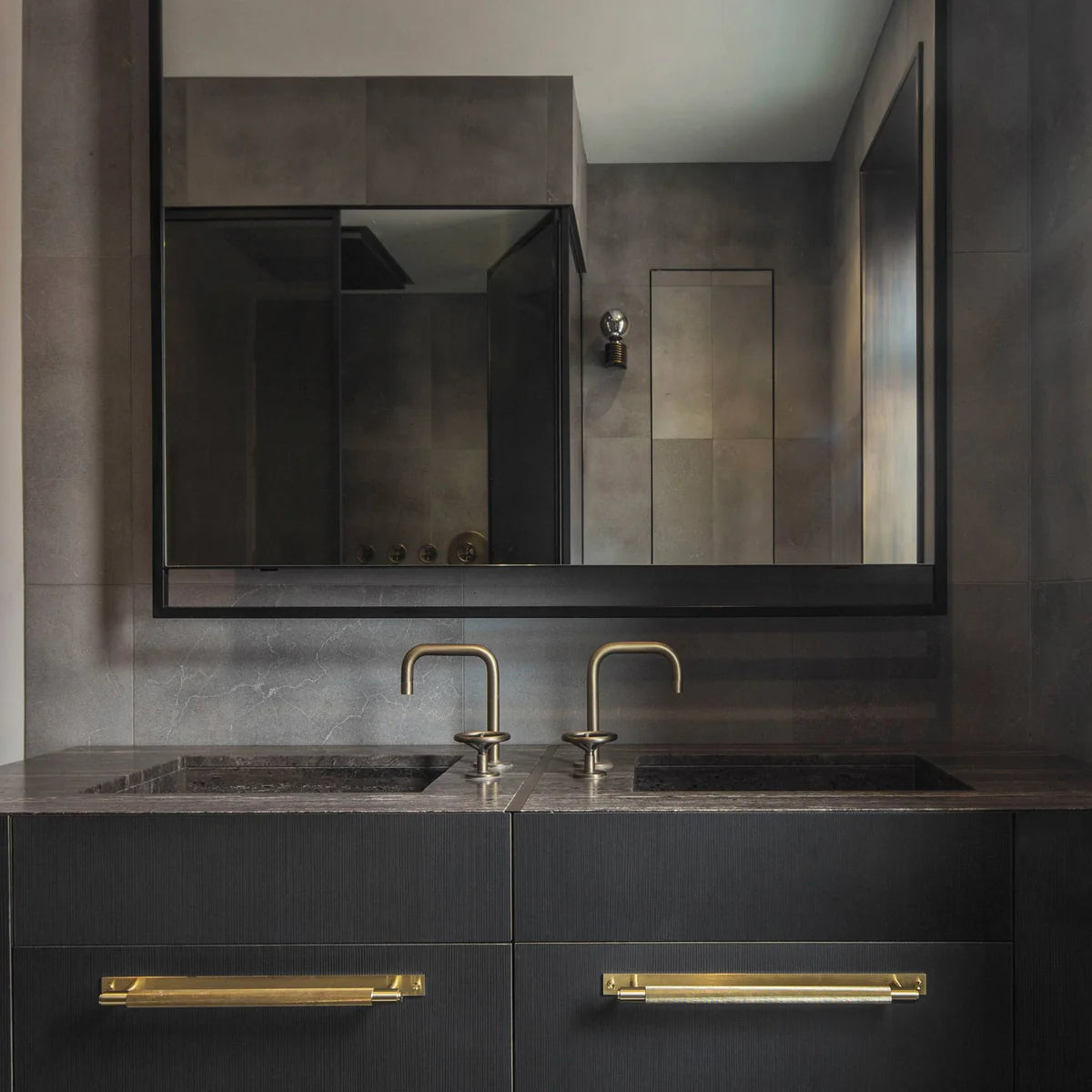 Buster + Punch Cross Pull Bar with Backplate in Brass finish in a modern dark bathroom vanity setting