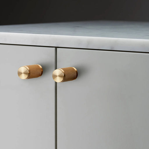 Buster + Punch Furniture Knob Cross in brass finish mounted on cabinetry