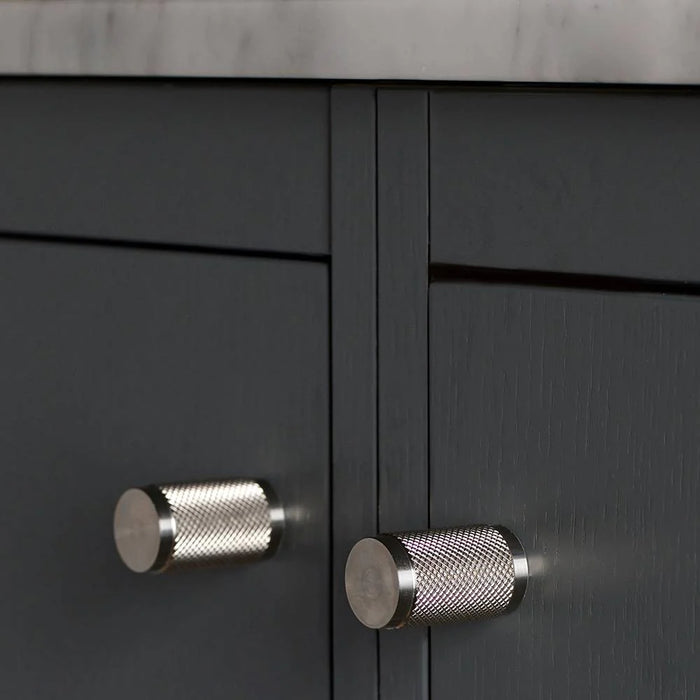 Close-up of Buster + Punch Furniture Knob Cross in steel finish on dark cabinetry