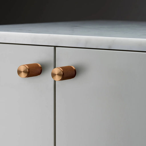 Buster + Punch Furniture Knob Cross in warm sunset finish installed on cabinet doors