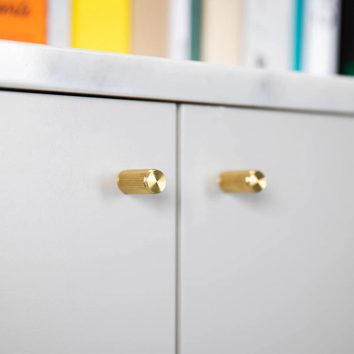 Buster + Punch Furniture Knob Linear in Brass installed on light grey cabinet doors