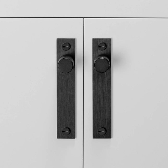 Full-length Buster + Punch Cross Black furniture knob plates on cabinetry