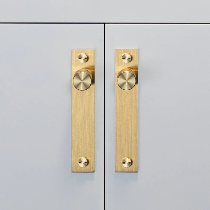 Brass Buster + Punch Cross furniture knob plates installed on cabinet doors